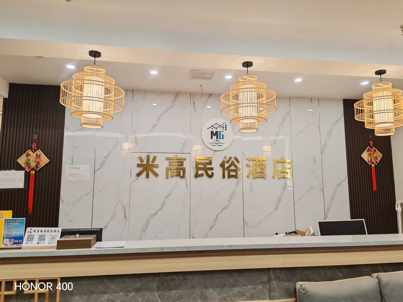 米高民俗酒店实拍 - 前台实拍：大理石背景墙、金色店名字样与竹编吊灯